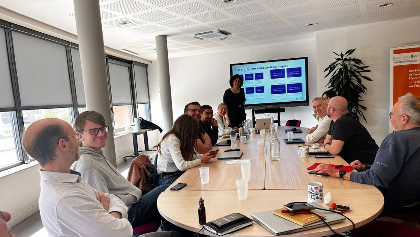 Groupe en formation FormIALab autour d'une table, Yaelle David présente le catalogue formialab.fr à l'écran, chez Plaine Vallée